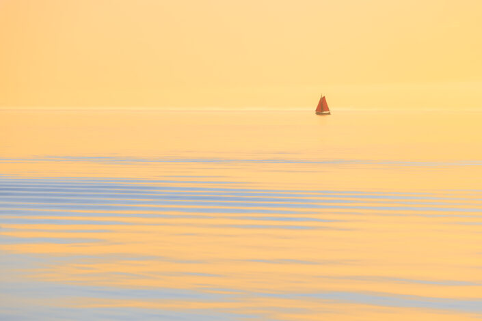 Een zeilschip op het IJsselmeer tijdens zonsondergang
