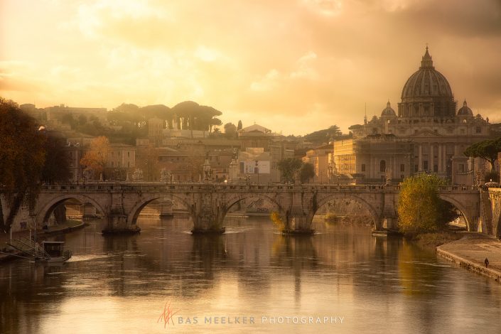 View over the Tiber in Rome with the Ponte Sant'Angelo and Saint Peters Church in the backgrpound on a sunny autumn afternoon with warm golden light - Rome, Italy