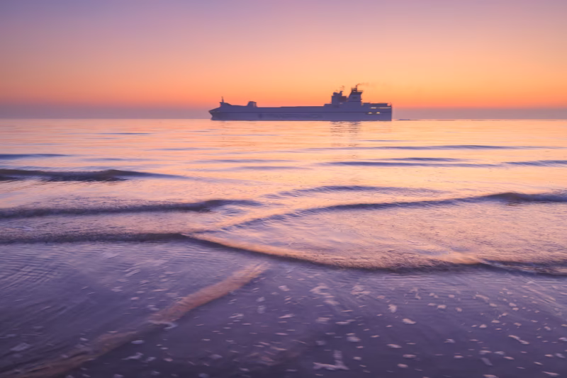 Een schip vaart voorbij op het strand van Dishoek