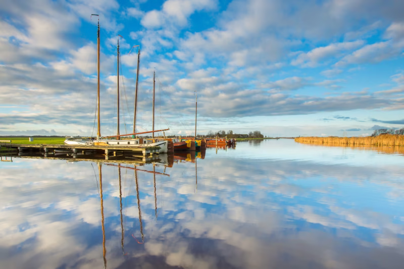 De haven van Sloten in Friesland met zeilboten en een mooie weerspiegeling van de wolken in het water