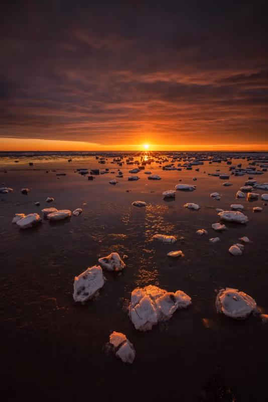 Ijsschotsen op de Waddenzee in de winter met een ondergaande zon
