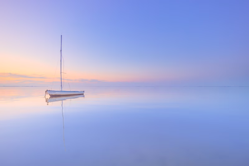 Zonsondergang bij Krabbendijke met een zeilboot in het water