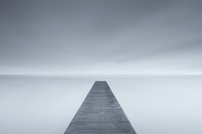 Into Nothingness - a cold morning on a misty Autumn day at the lake with a dark grey sky