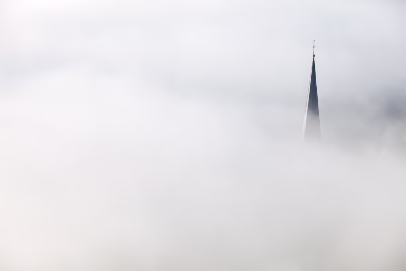 Een kerktoren steekt uit de mist aan de Moezel in Duitsland