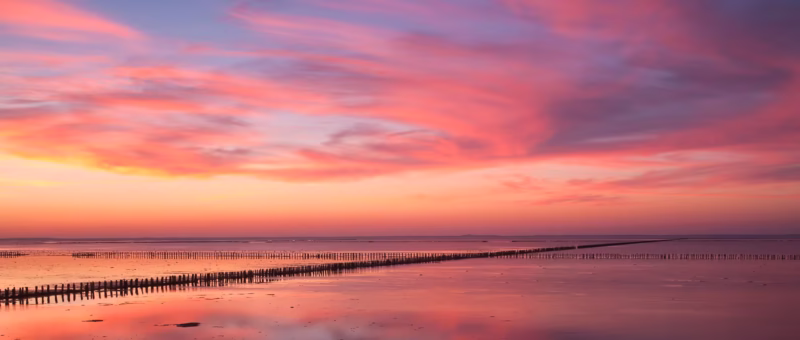 Een panorama van de zonsondergang op de Waddenzee met avondrood