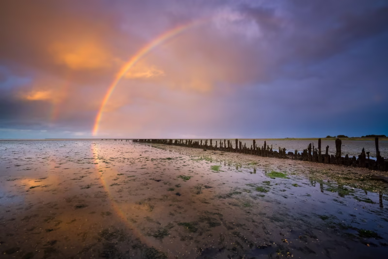 Zonsondergang boven de Waddenzee met een regenboog