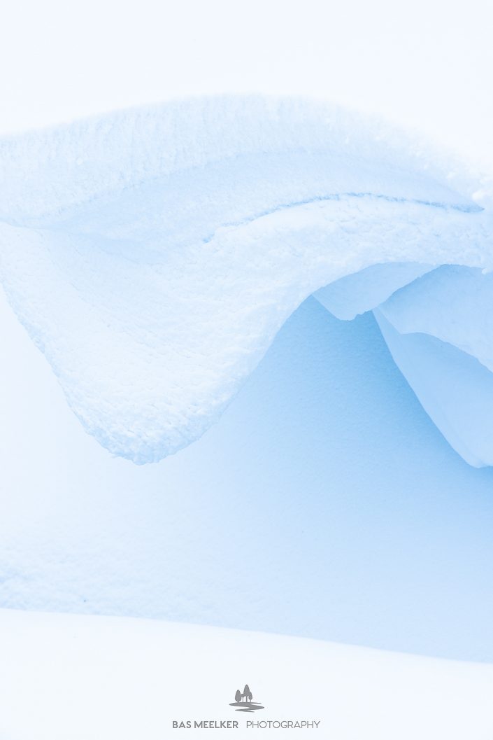 Minimalistische en abstracte structuren en details in de sneeuw veroorzaakt door sneeuwduinen met lijnen en vormen. Een abstract beeld.