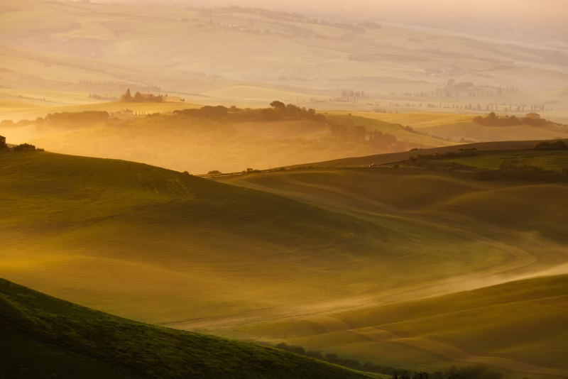 Mist tussen de heuvels tijdens een mooie zonsopkomst in Toscane, Italië