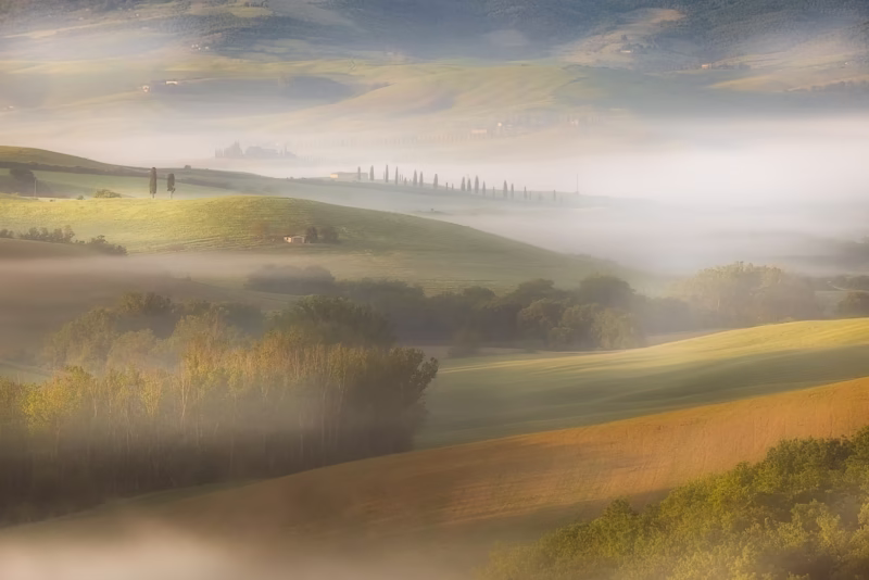 Een mooi mistig heuvellandschap tijdens de zonsopkomst in Toscane, Italië,
