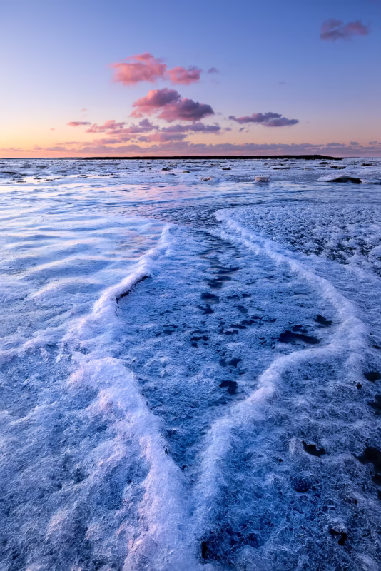 Zonsondergang in de winter op de Waddenzee bedekt met ijs