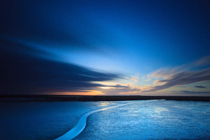 Een kreek op de Waddenzee tijdens het blauwe uurtje na zonsondergang