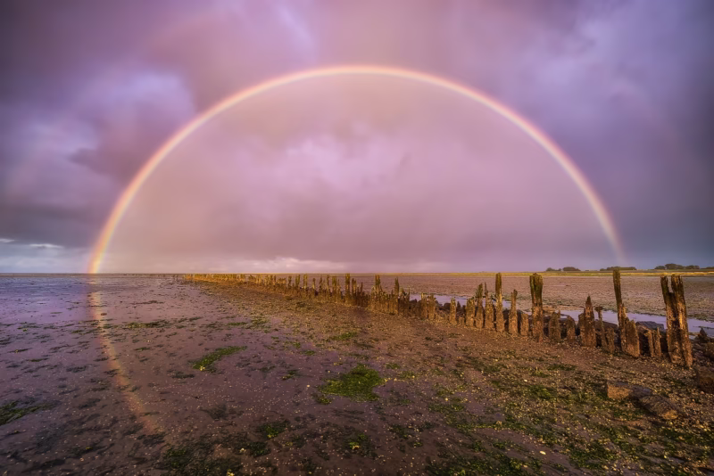 Een regenboog boven de Waddenzee na een regenbui