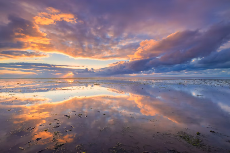 De Waddenzee met een mooie weerspiegeling van de wolkenlucht