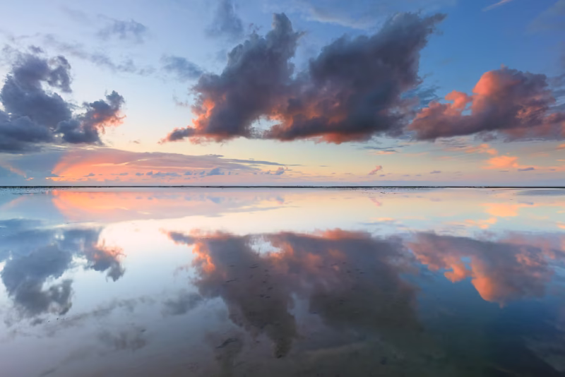 Een mooie weerspiegeling van de wolkenlucht op de Waddenzee tijdens zonsondergang