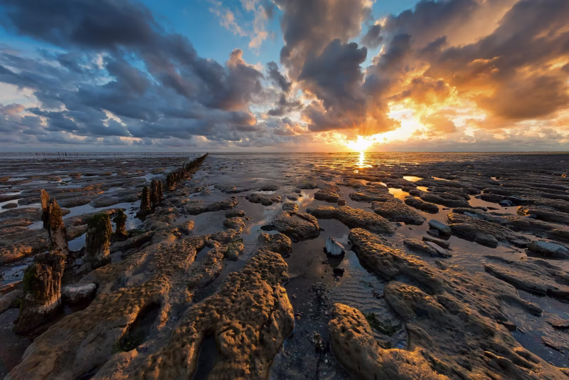 Een prachtige wolkenlucht boven de Waddenzee bij laag water tijdens zonsondergang