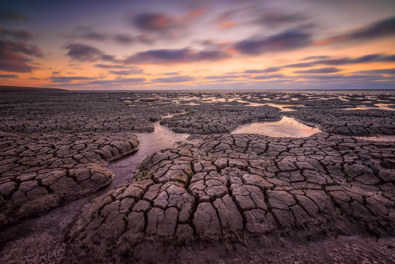 De Waddenzee bij laag water met de structuren van de klei tijdens zonsondergang