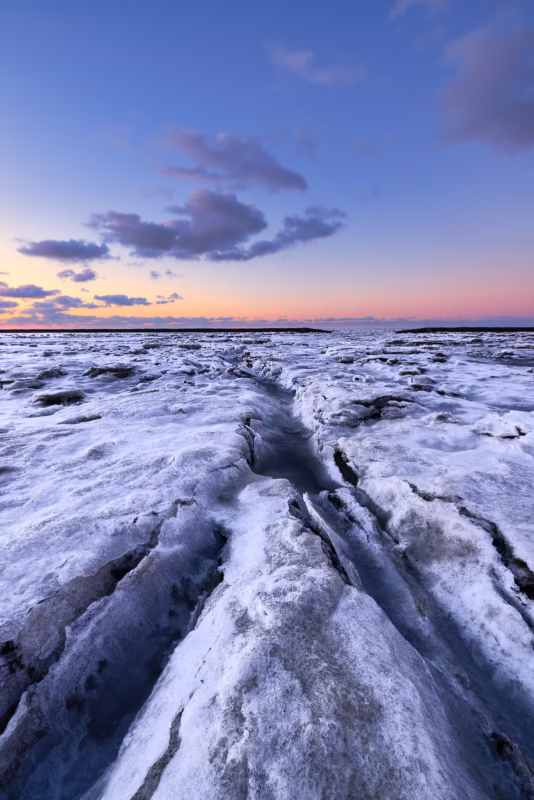 IJs bedekt de Waddenzee tijdens een koude winterse zonsondergang