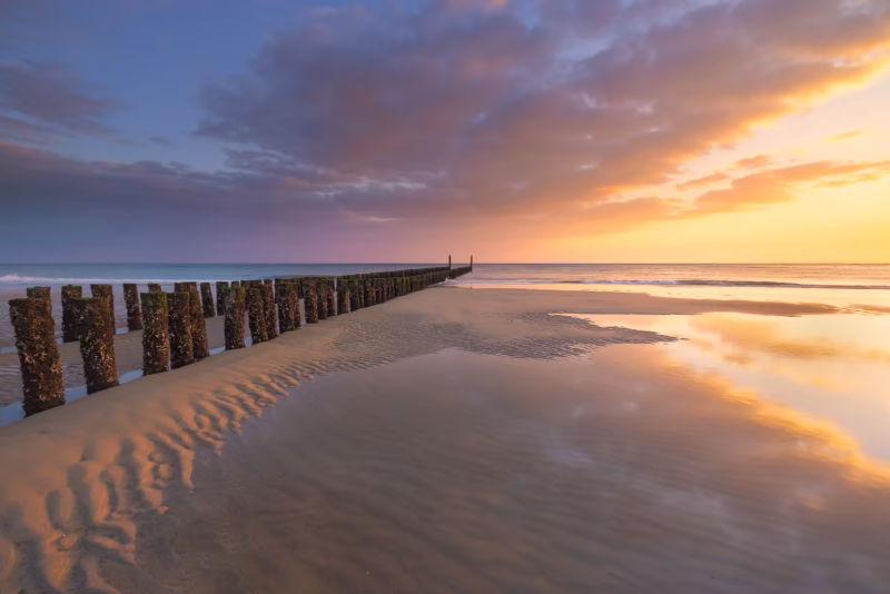 Zonsondergang op het strand van Zoutelande met een palenrij in de zomer