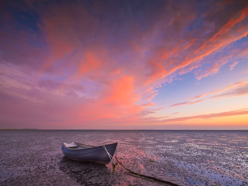 Een drooggevallen bootje op de Oosterschelde tijdens een mooie zonsopkomst
